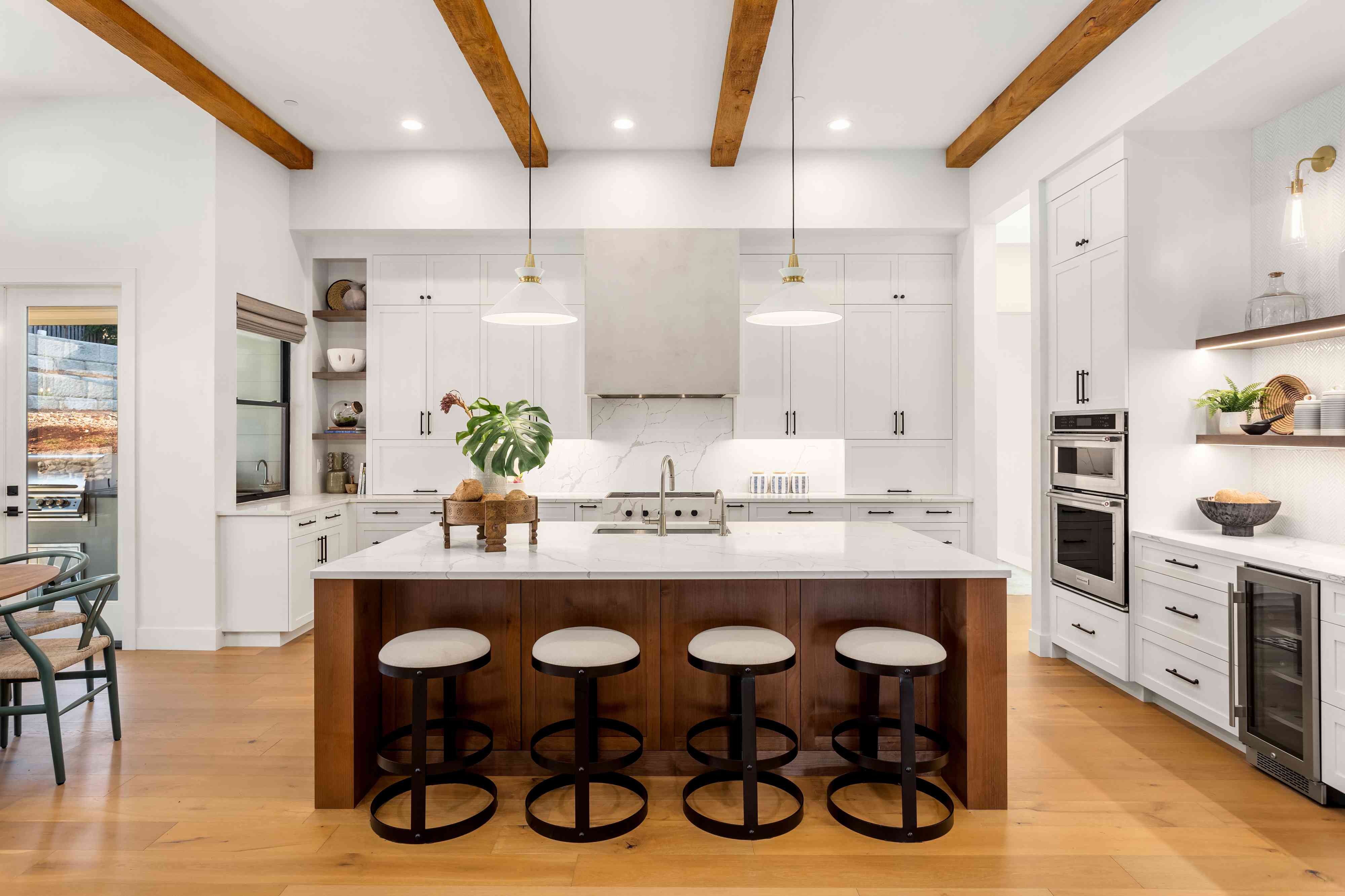 Modern luxury white kitchen with island and wood-beamed ceiling